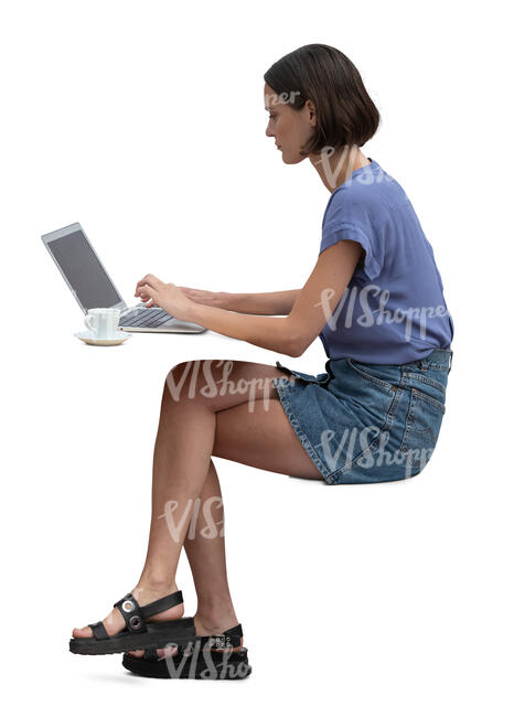 woman sitting at a  table and working with computer and drinking coffee