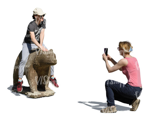 woman taking a picture of her friend posing with a statue