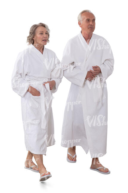 two older people wearing white bathrobes walking