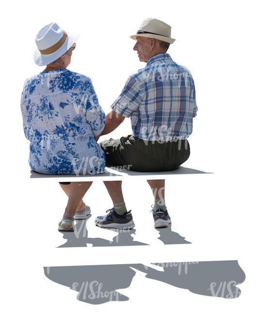 two backlit older people sitting on a bench