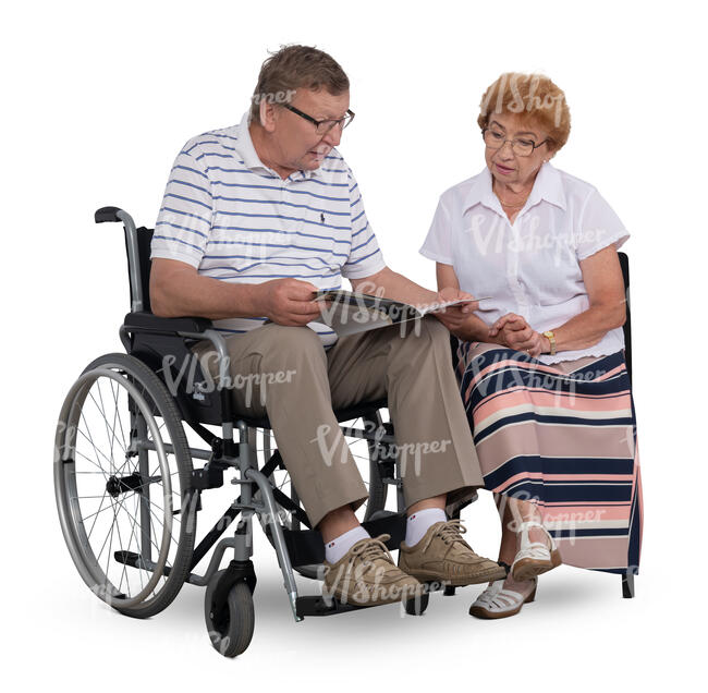 man in a wheelchair looking at a book together with his wife