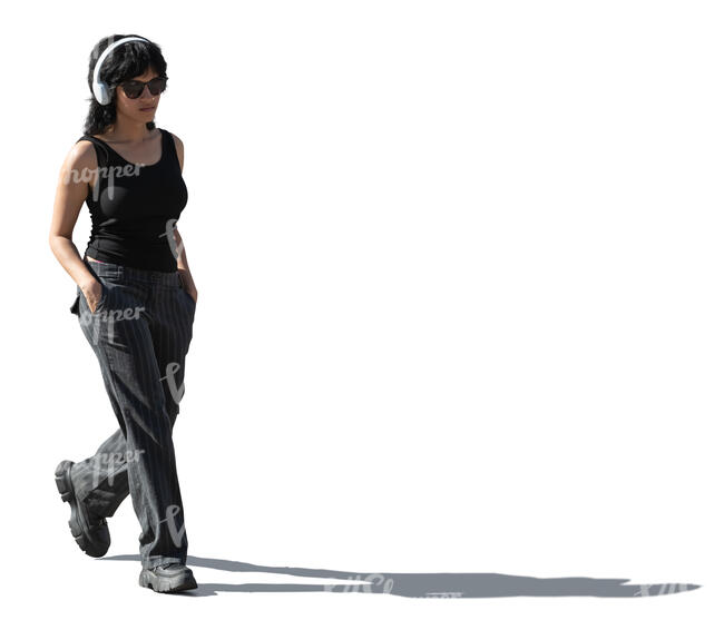 cut out sidelit woman with headphones walking with hands in her pocket