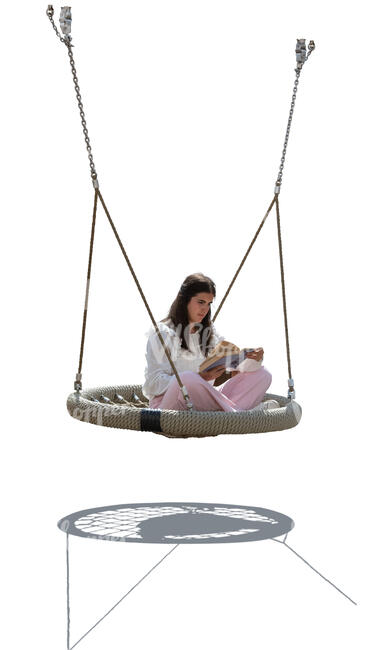 backlit woman sitting in an outdoor swing and reading