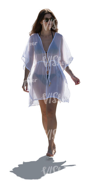 backlit woman wearing a light beach cover up dress walking