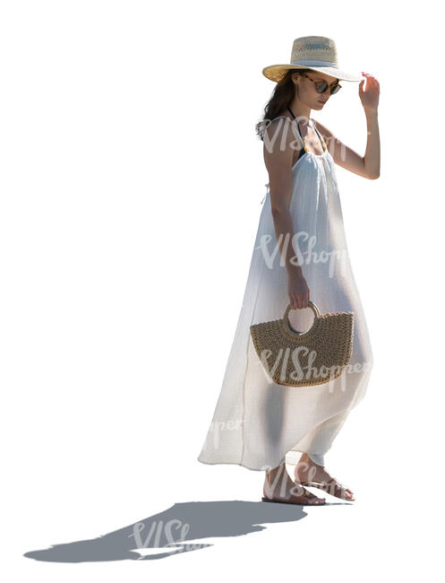 backlit woman in a long white beach dress walking