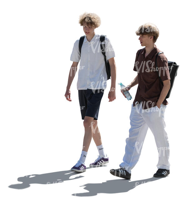 two backlit teenage boys walking