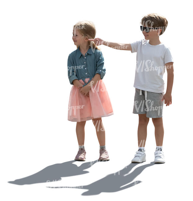 two backlit children standing and pointing at smth