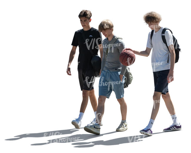 three backlit teenage boys with a basketball walking