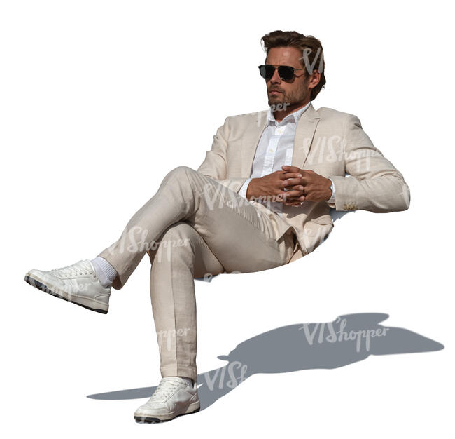 man in a white suit sitting on a sofa