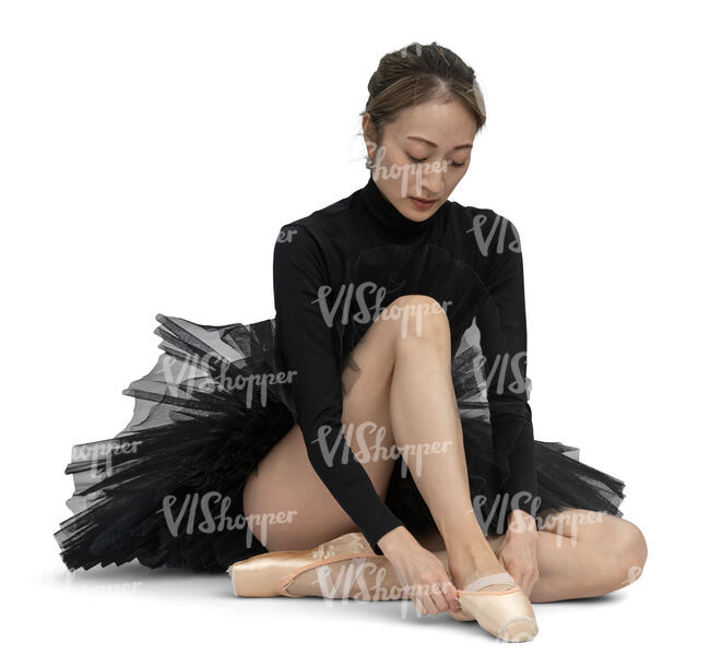 ballerina in a black ballet dress putting on her shoes