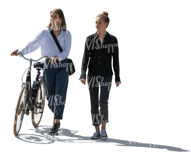 two backlit women with a bike walking