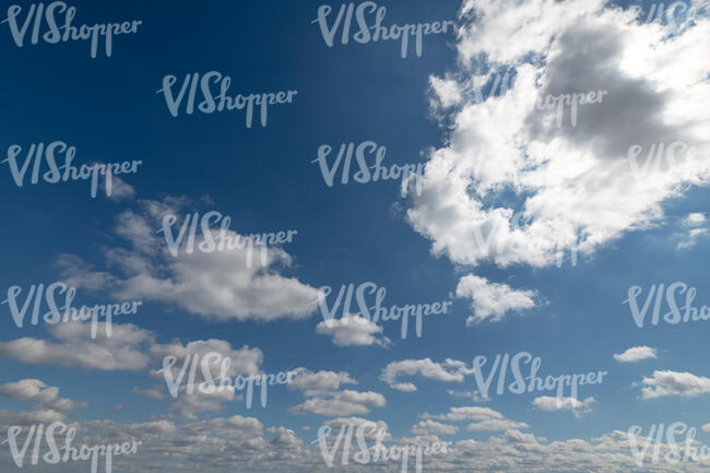 daytime sky with sun behind small white clouds